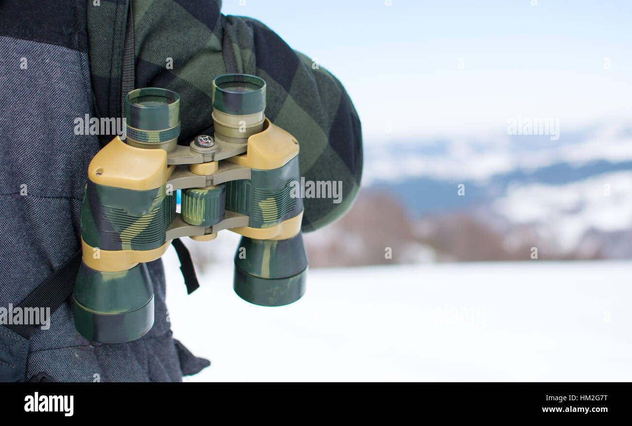 Man with binoculars exploring snowy mountain scenery Stock Photo