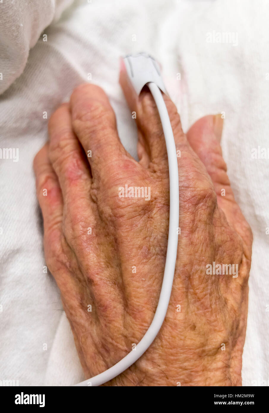 Elderly hand with a pulse meter on index finger. Stock Photo