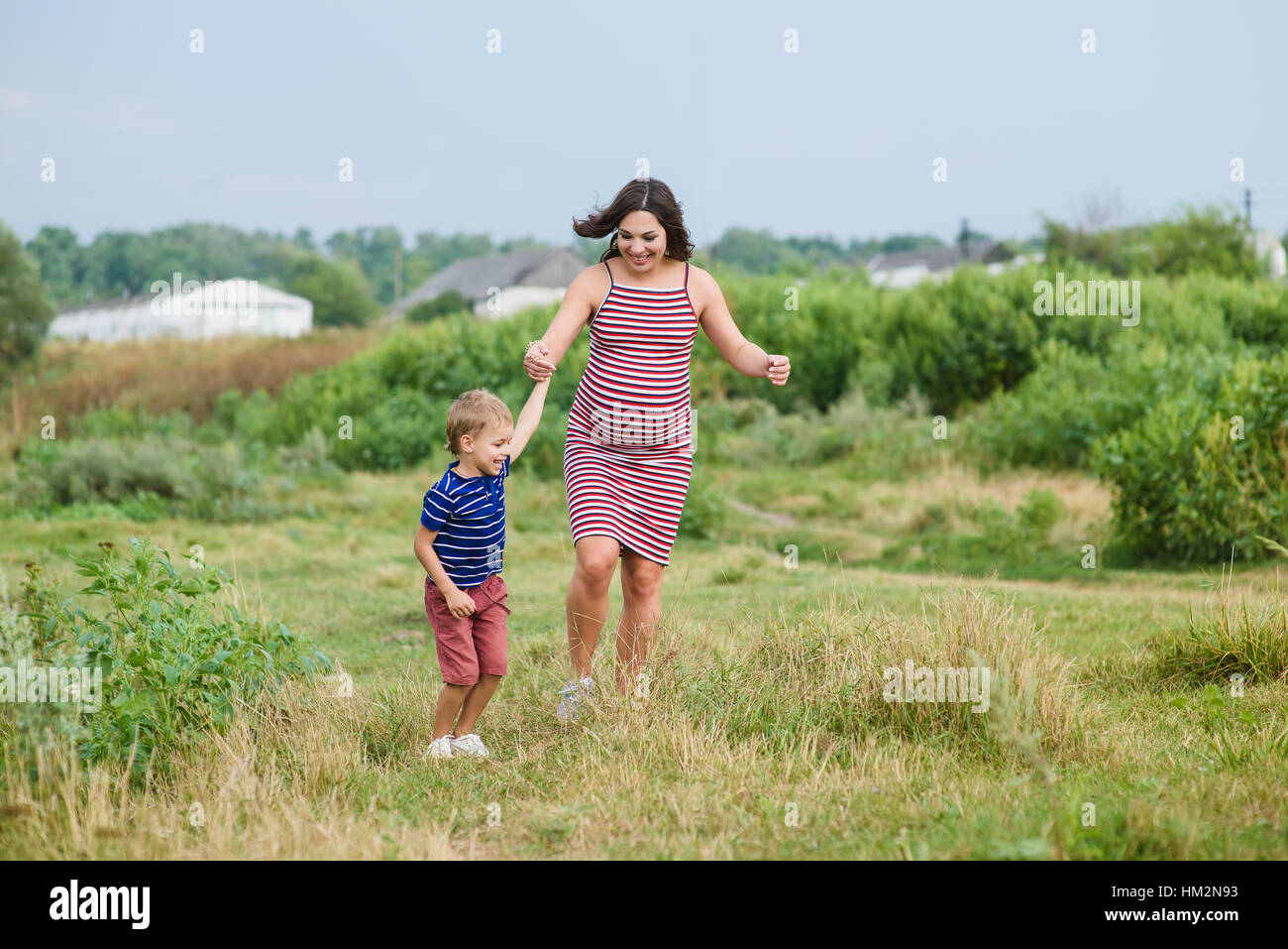 Pregnant woman walking countryside with her son. Stock Photo
