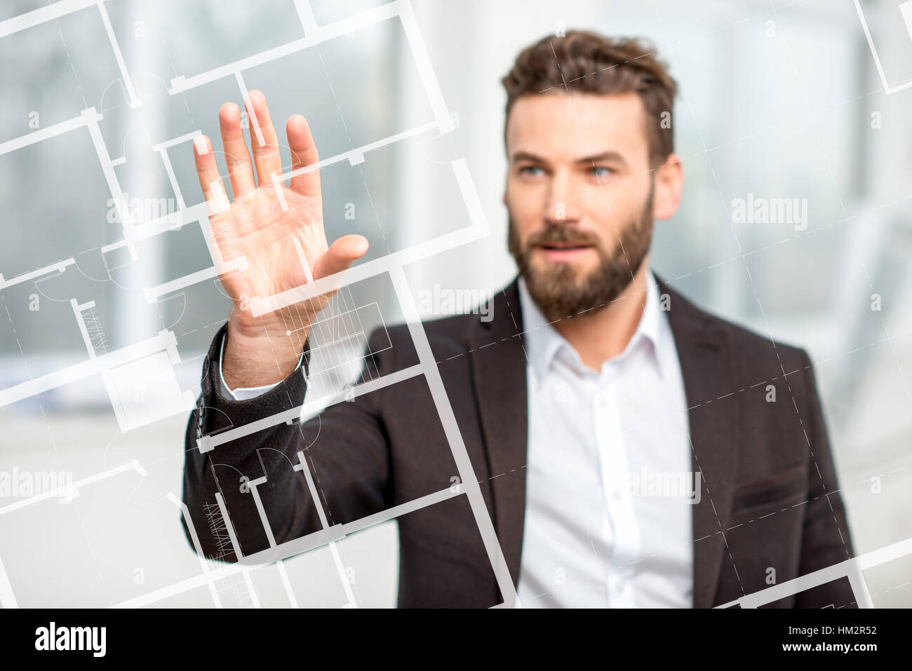 Architect or designer working with plan drawing on the virtual screen standing in the white room Stock Photo