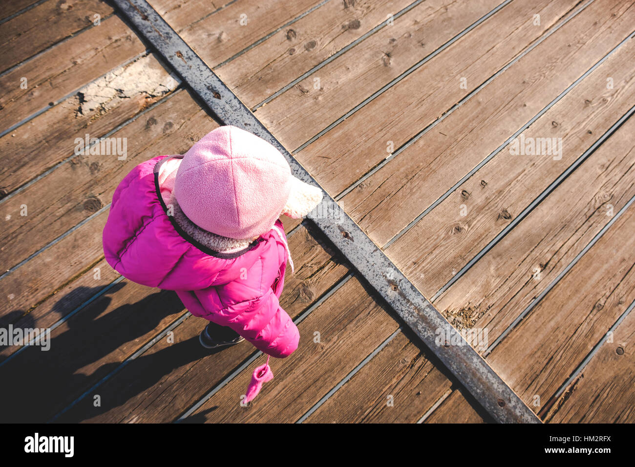 baby girl walk wood floor pink winter clothes top view Stock Photo