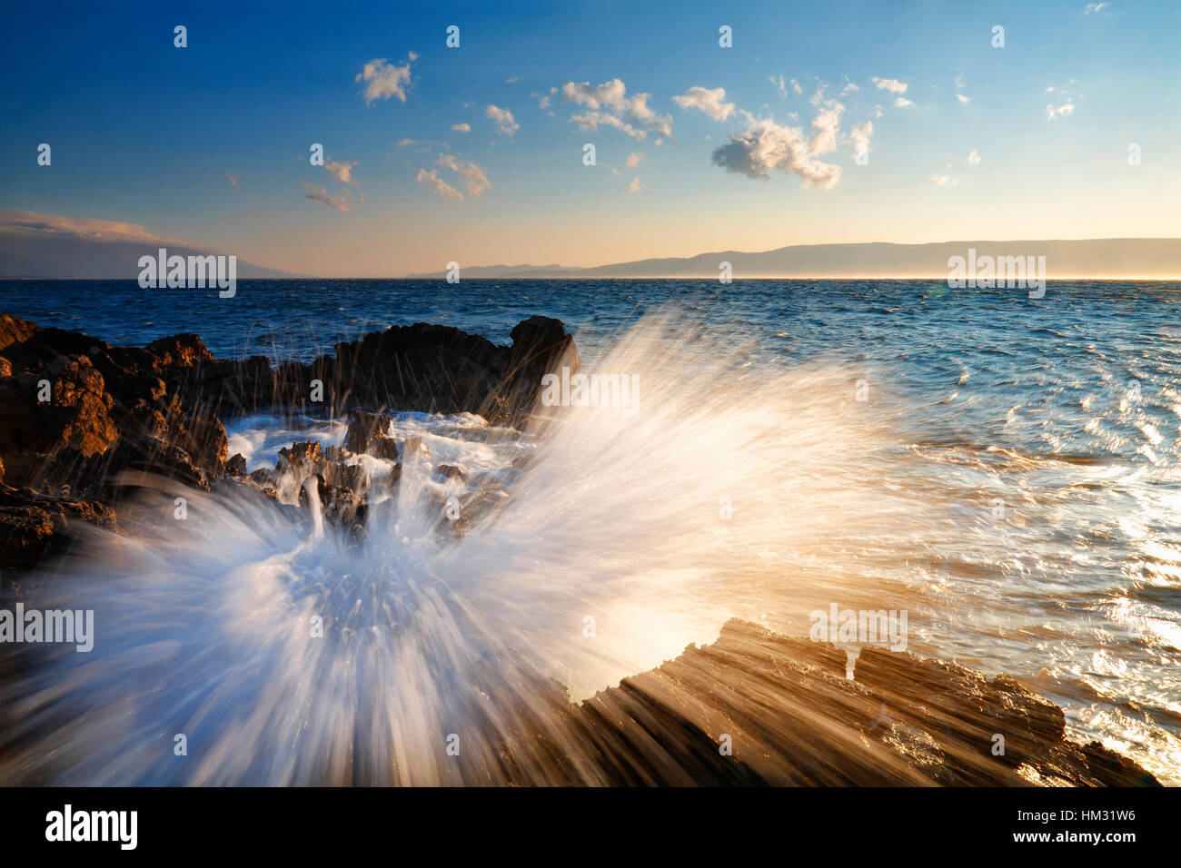 Wave splashing rock at sunset. Nature landscape. Stock Photo