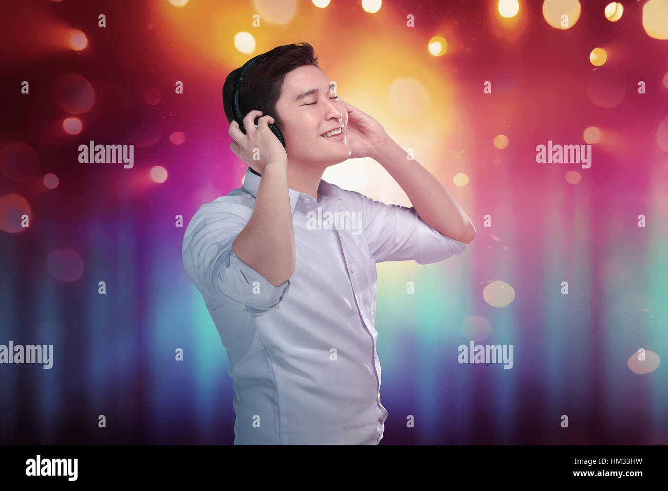 Cheerful asian man enjoying his favorite music in headphones with bokeh background Stock Photo