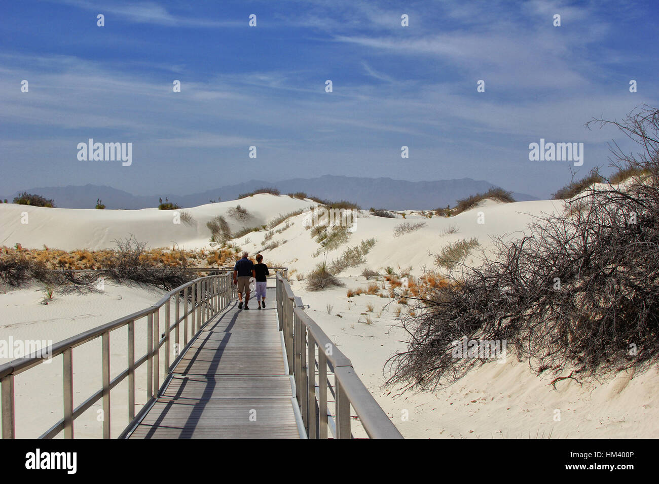 A couples walks over the dunes on the boardwalk at White Sands National Monument. It is the world's largest gypsum dunefield Stock Photo