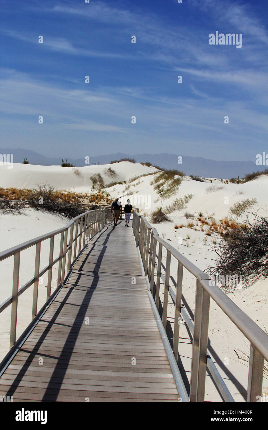 A couples walks over the dunes on the boardwalk at White Sands National Monument in Alamogordo, New Mexico. Stock Photo
