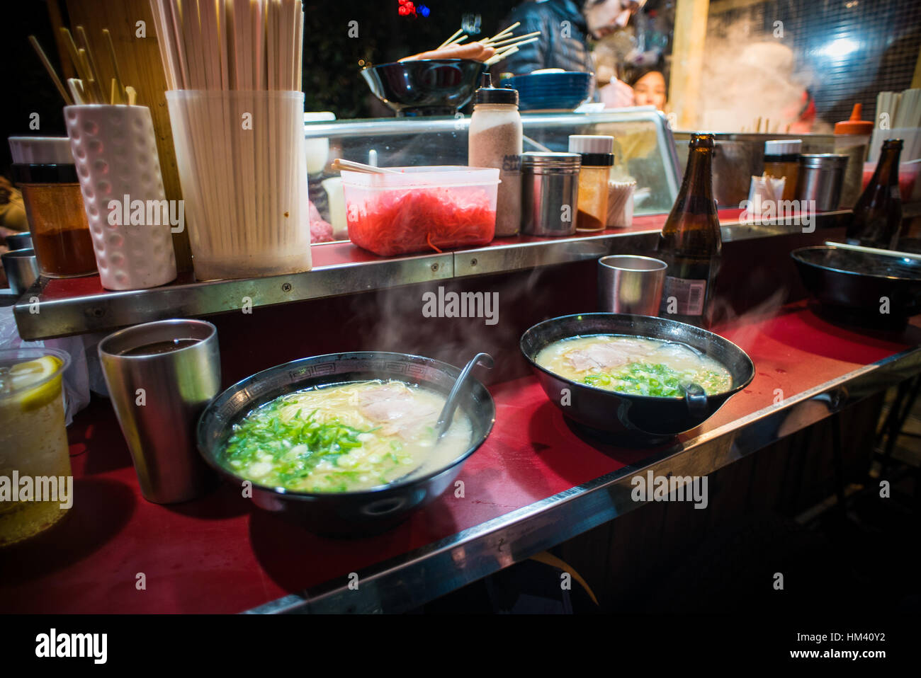 Two bowls of steaming hot ramen sit on a bar ledge in one of Fukuoka's famous yatai food carts Stock Photo