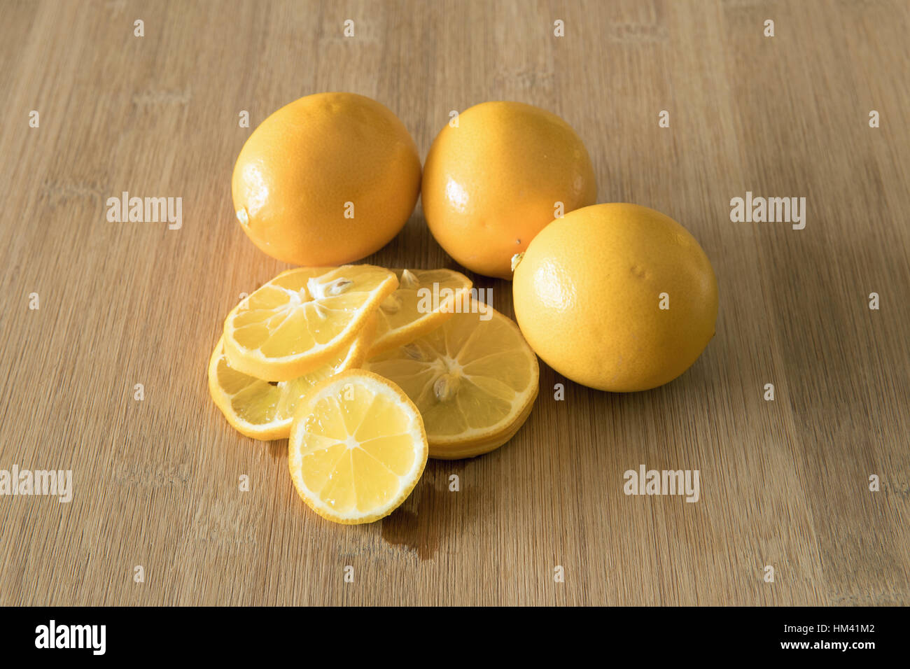 Sliced and unsliced lemons on cutting board Stock Photo