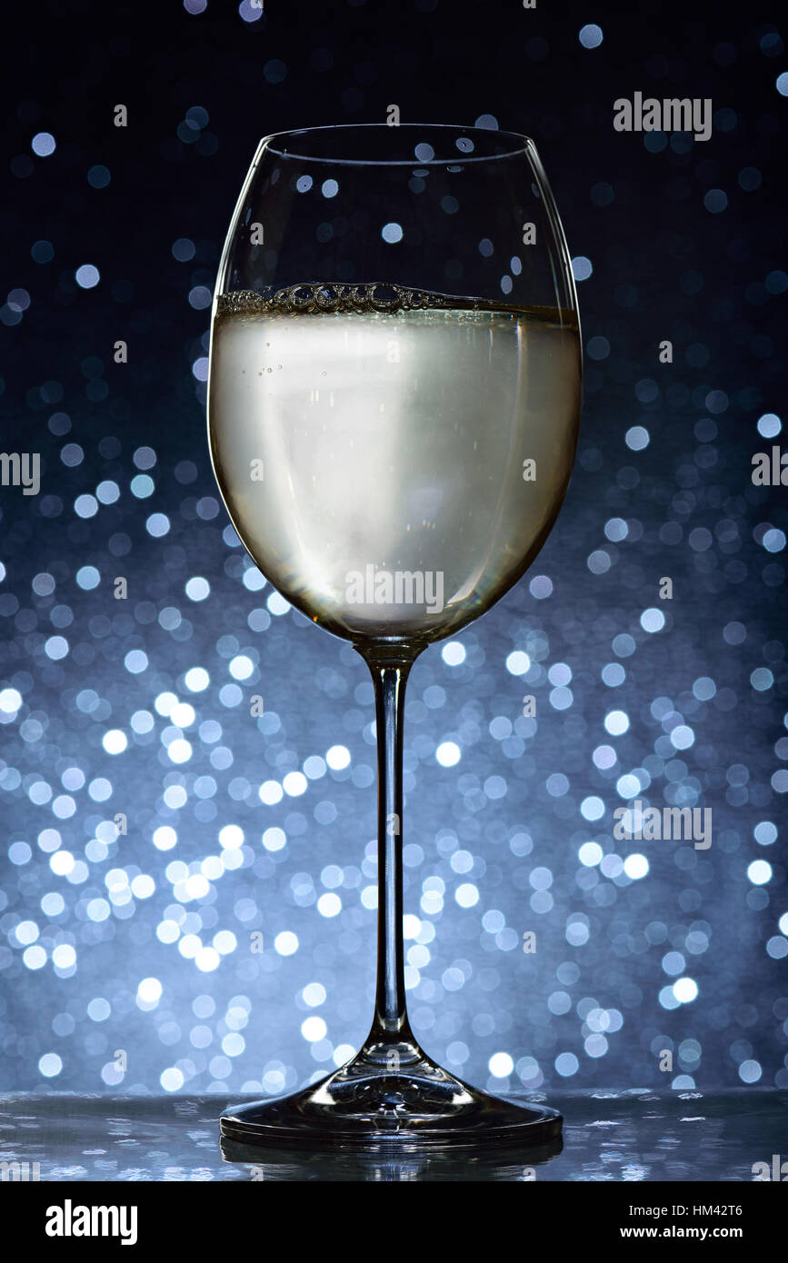 long glass with white wine on blue bokeh background Stock Photo