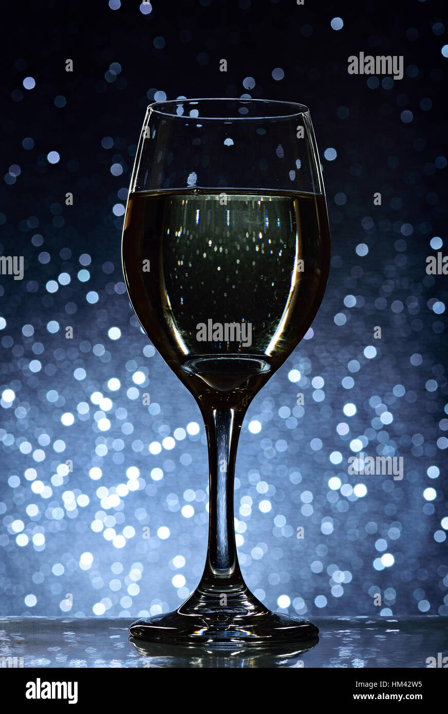 Glass with white wine on blue bokeh background Stock Photo