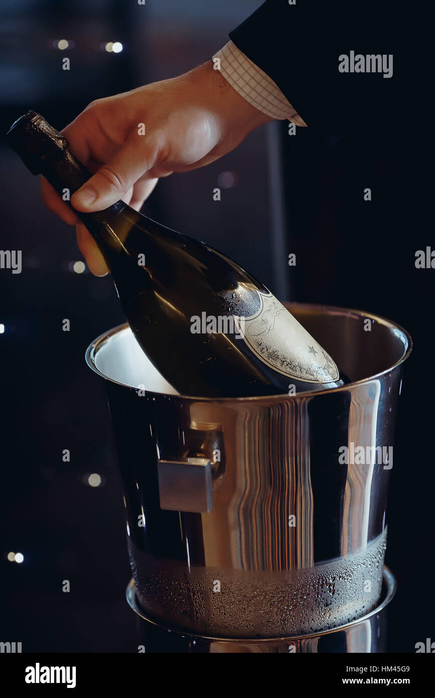 Hand holds a bottle of wine which is in bucket Stock Photo