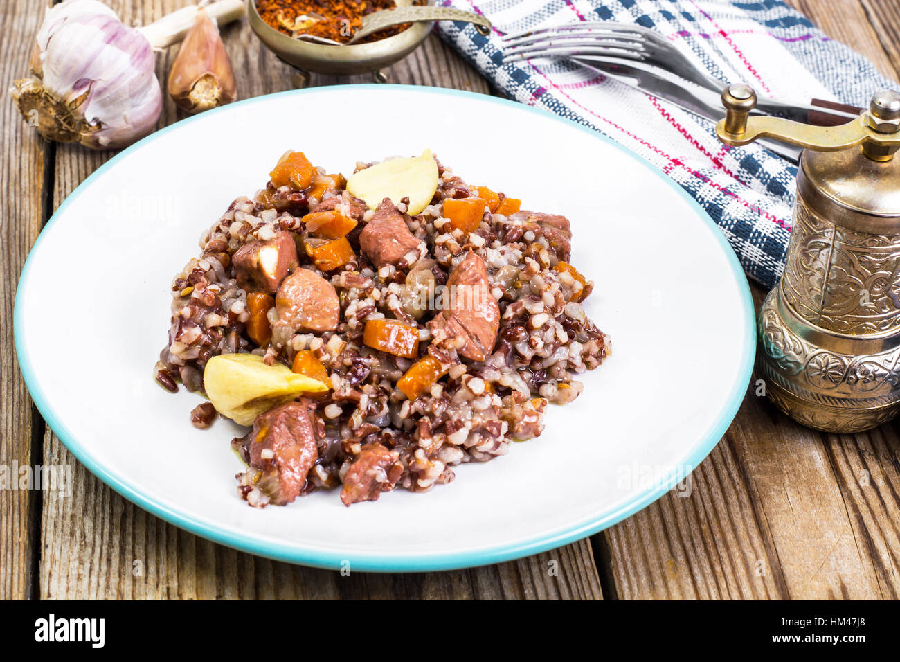 Pilaf with red rice with chunks of beef, carrots and garlic Stock Photo