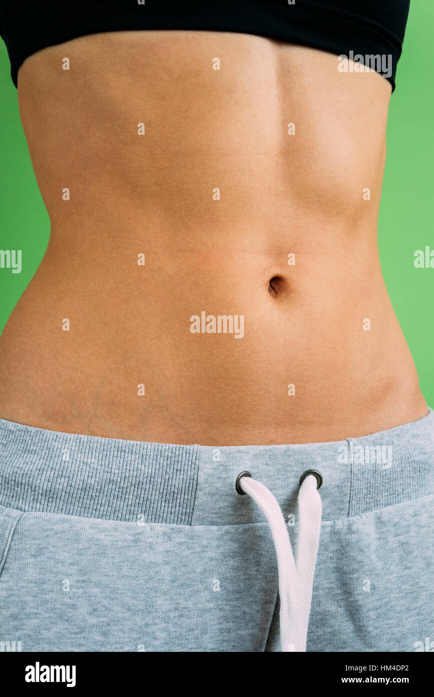 Belly slim girl in a sports pants on a green background, not isolated. Stock Photo