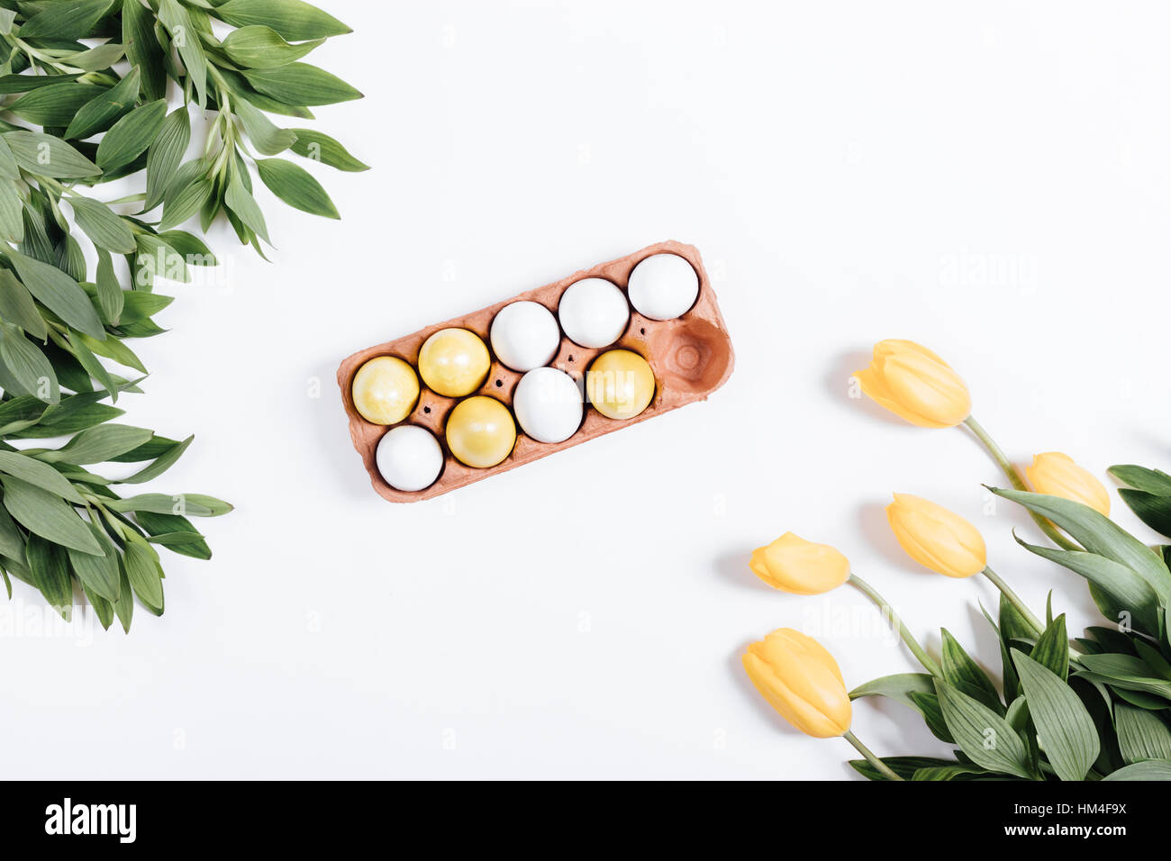 Easter composition: a tray with colored eggs and tulips on white ...