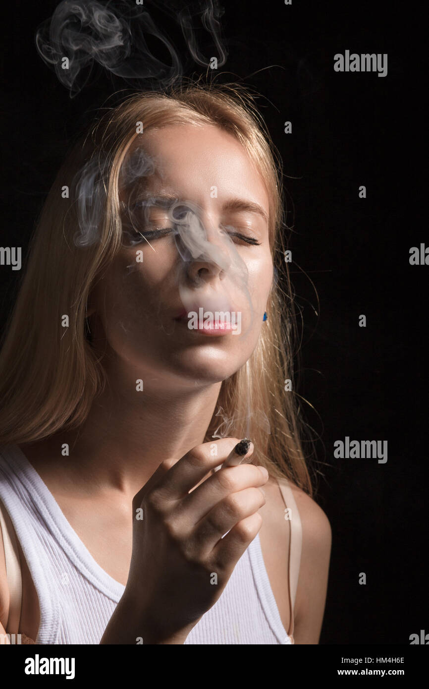 blond young woman smoking on black background Stock Photo - Alamy