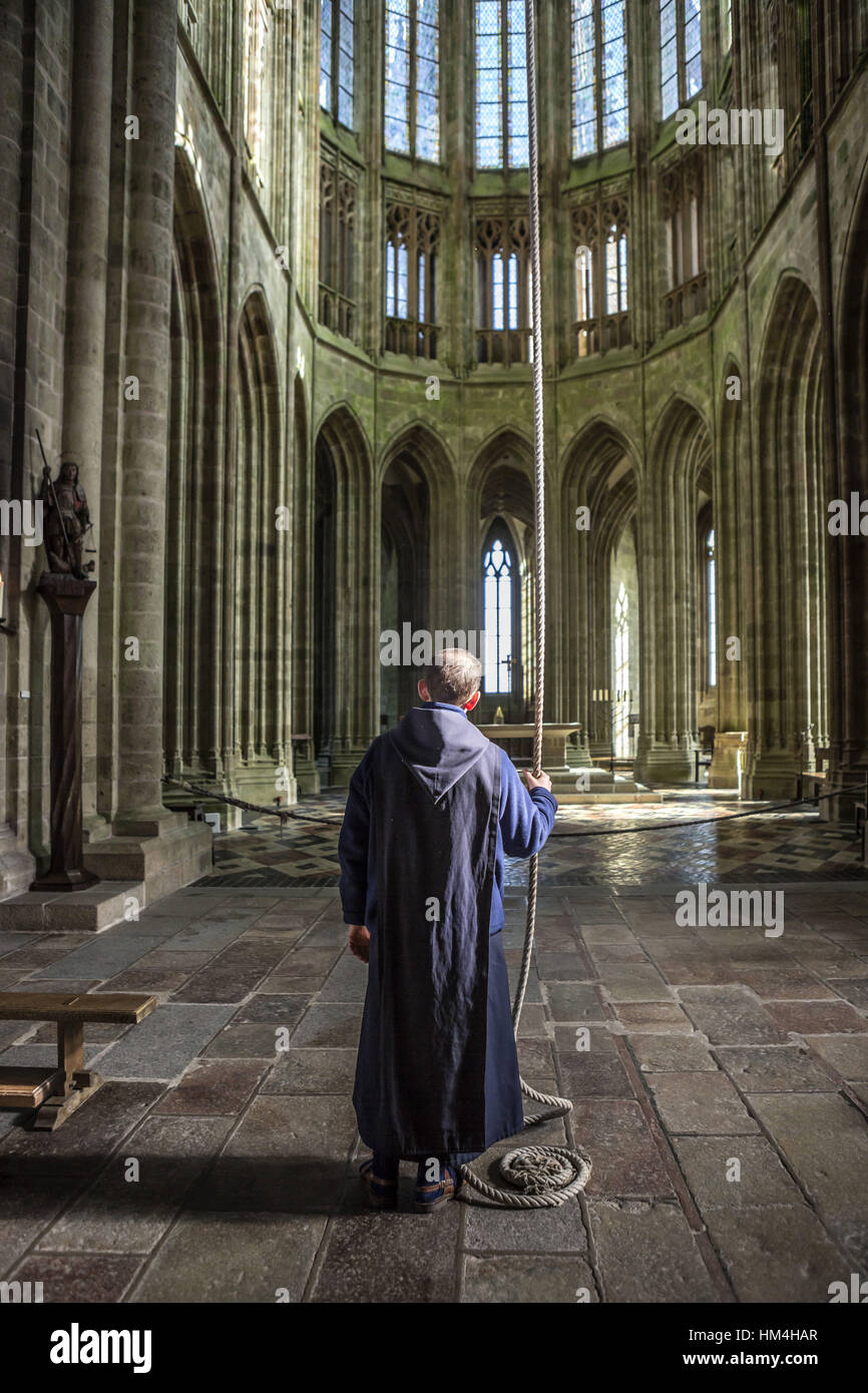 Mont Saint-Michel (Saint Michael's Mount), Normandy, north-western France: Back view of a brother sounding the bell of the abbey. Stock Photo