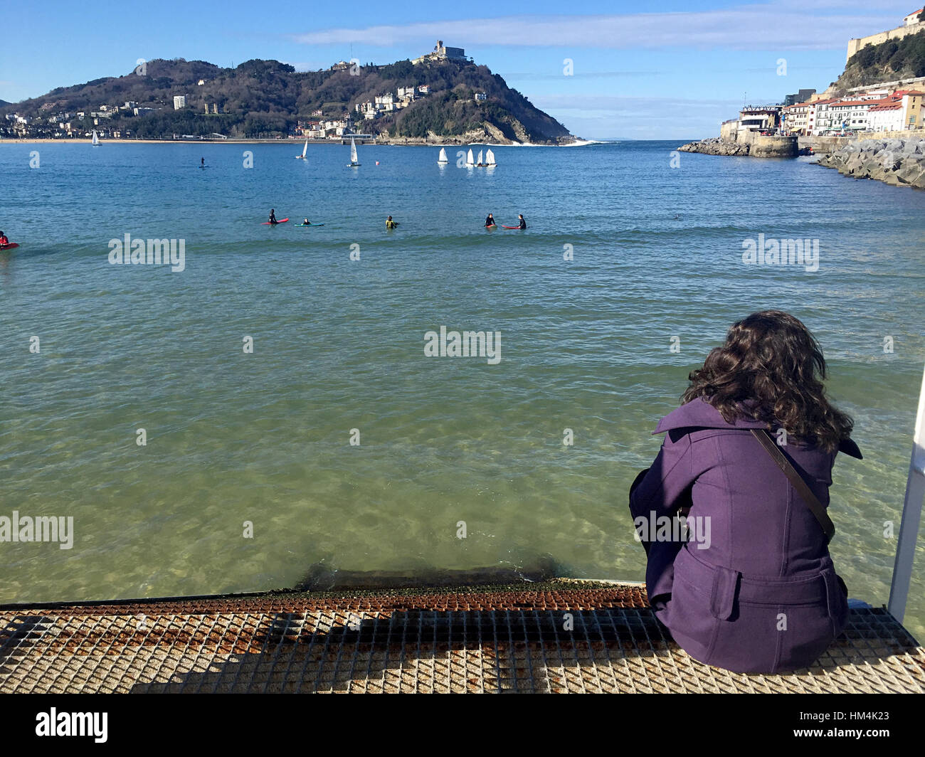 A girl sitting on the pier of Donostia-San Sebastian, Basque Country, City, Spain. The beach of La Concha Stock Photo