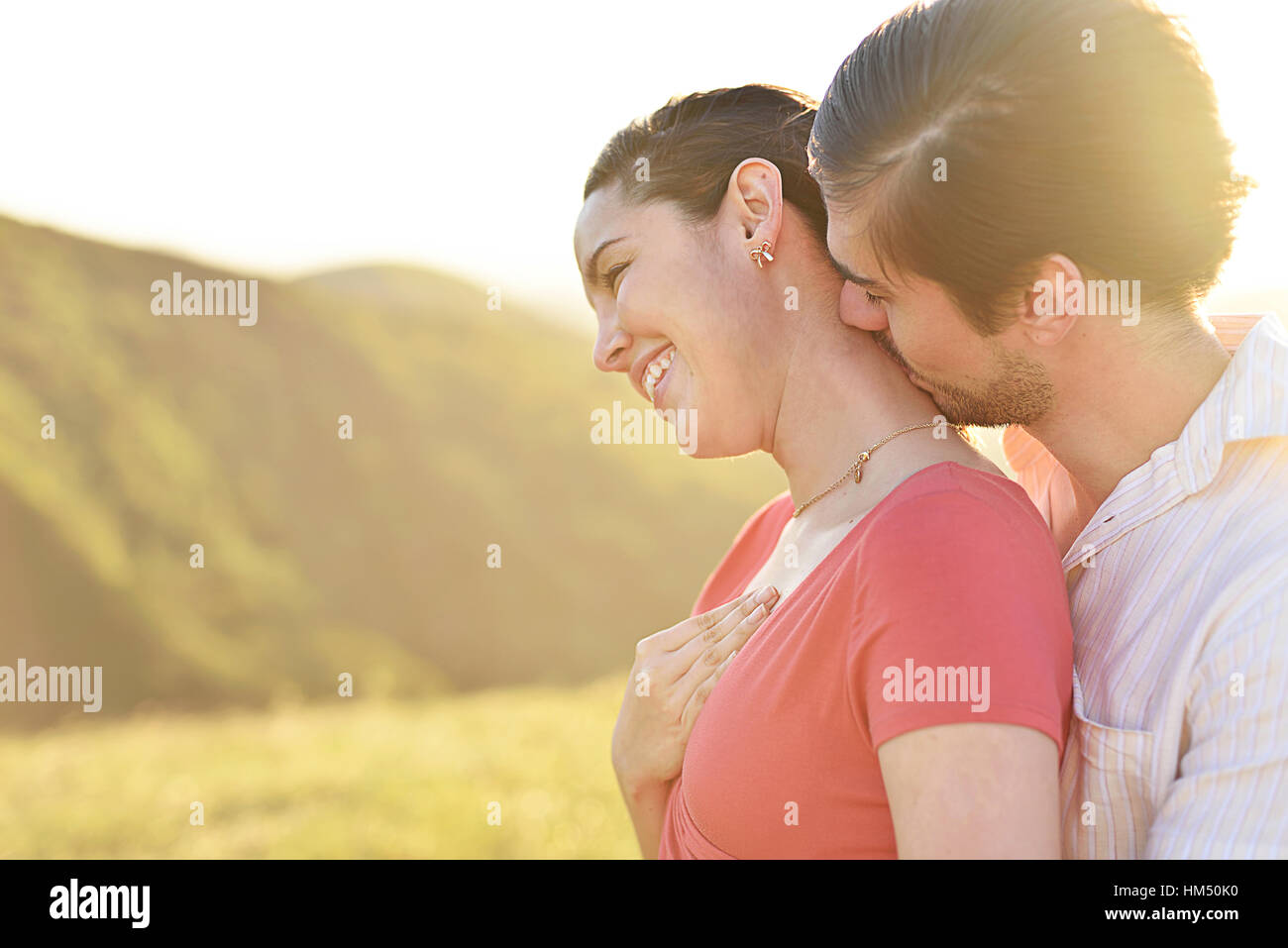 Man hugging and kissing in neck girl on sunny day Stock Photo