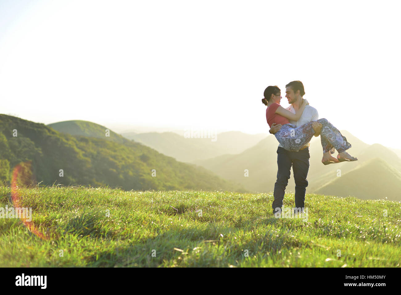 Couple in love in summer vacation in green hills Stock Photo
