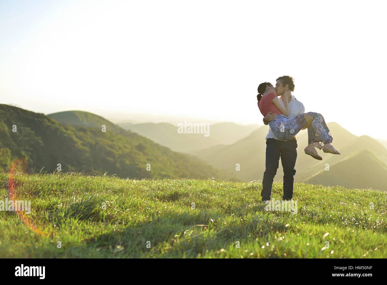 guy kissing girl on hands in summer green grass Stock Photo