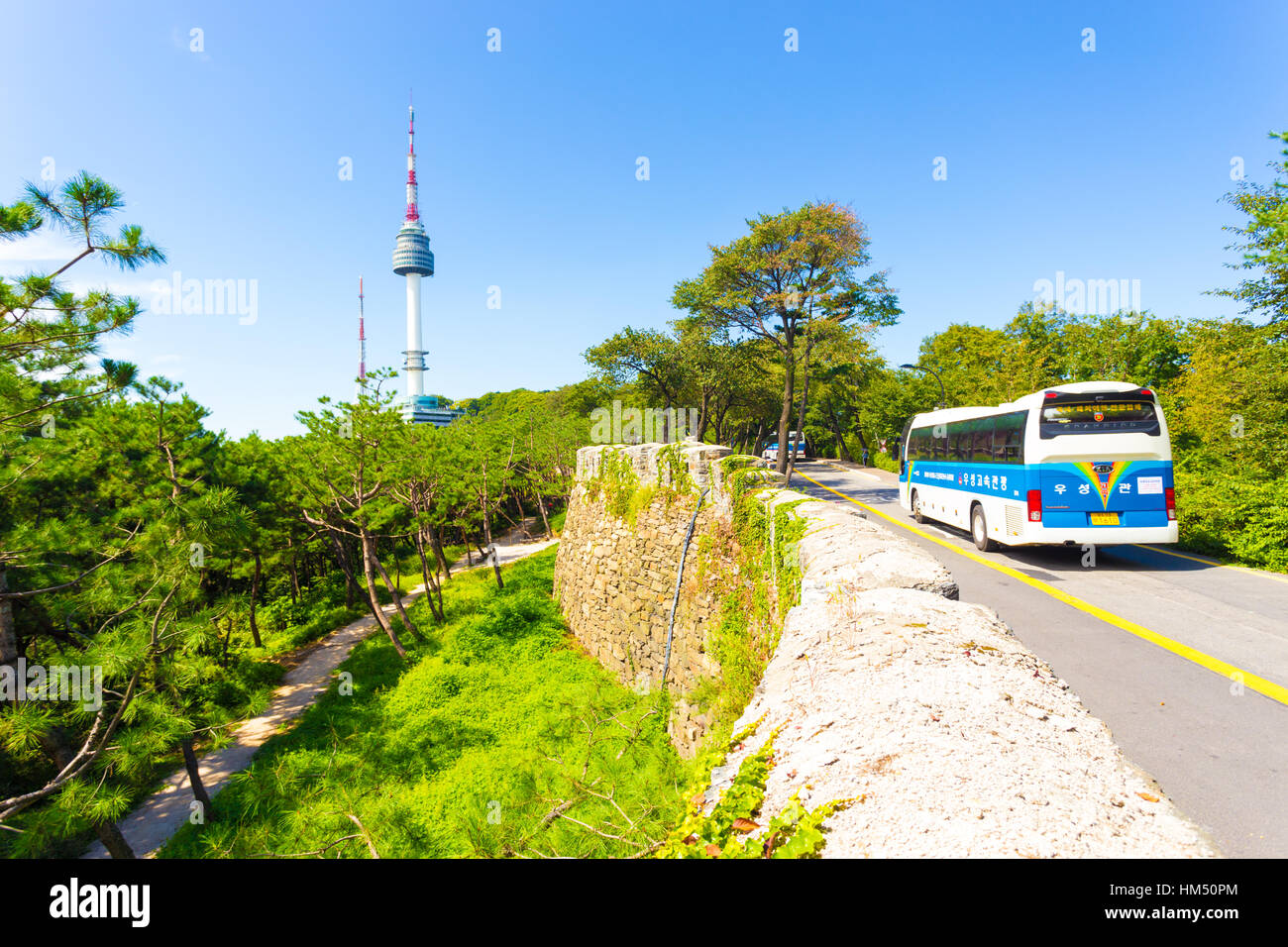 Tourist bus traveling on street along the old city wall with view of YTN Seoul Tower broadcast antenna on Namsan mountain Stock Photo