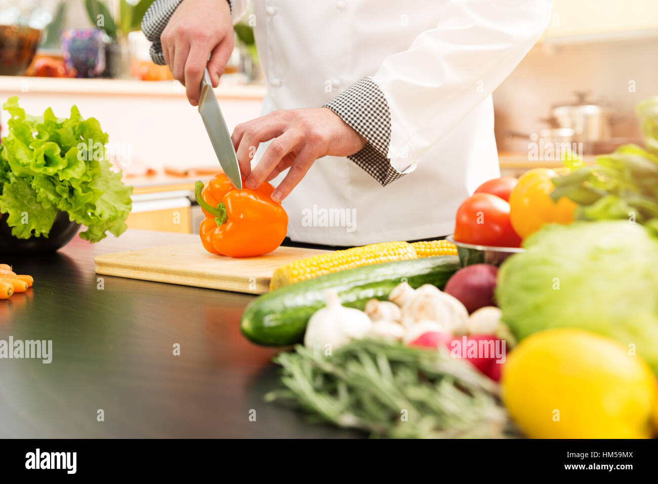 cook preparing vegetable salad in domestic kitchen Stock Photo