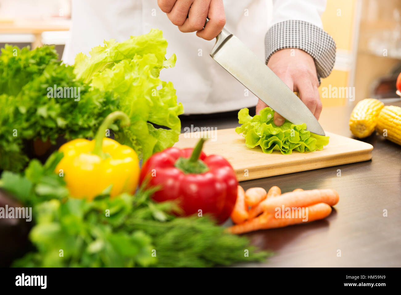 cook cutting lettuce, preparing vegetable salad in kitchen Stock Photo