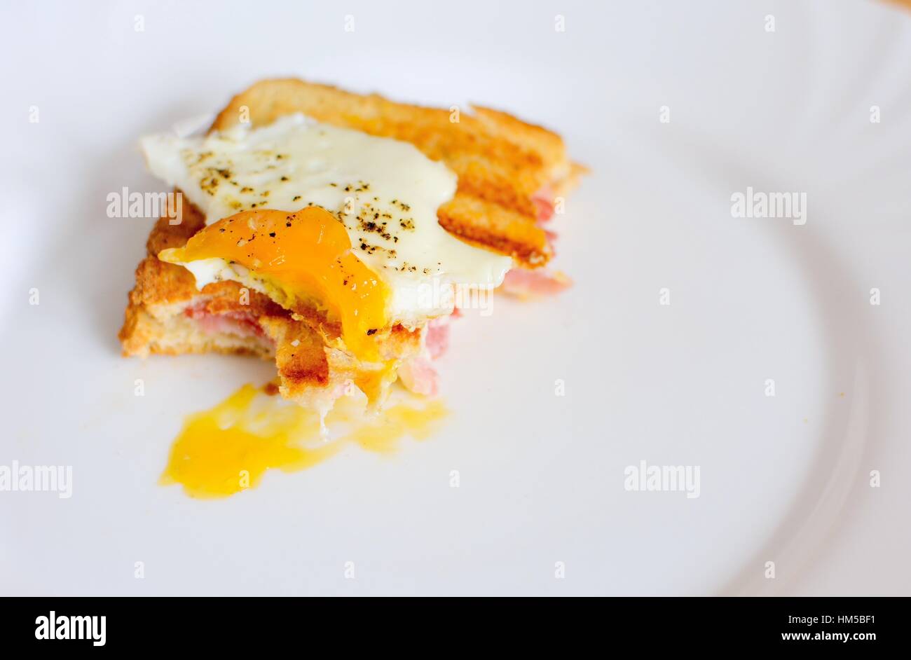 Leftover of ham and cheese toast with fried egg on top with missing
