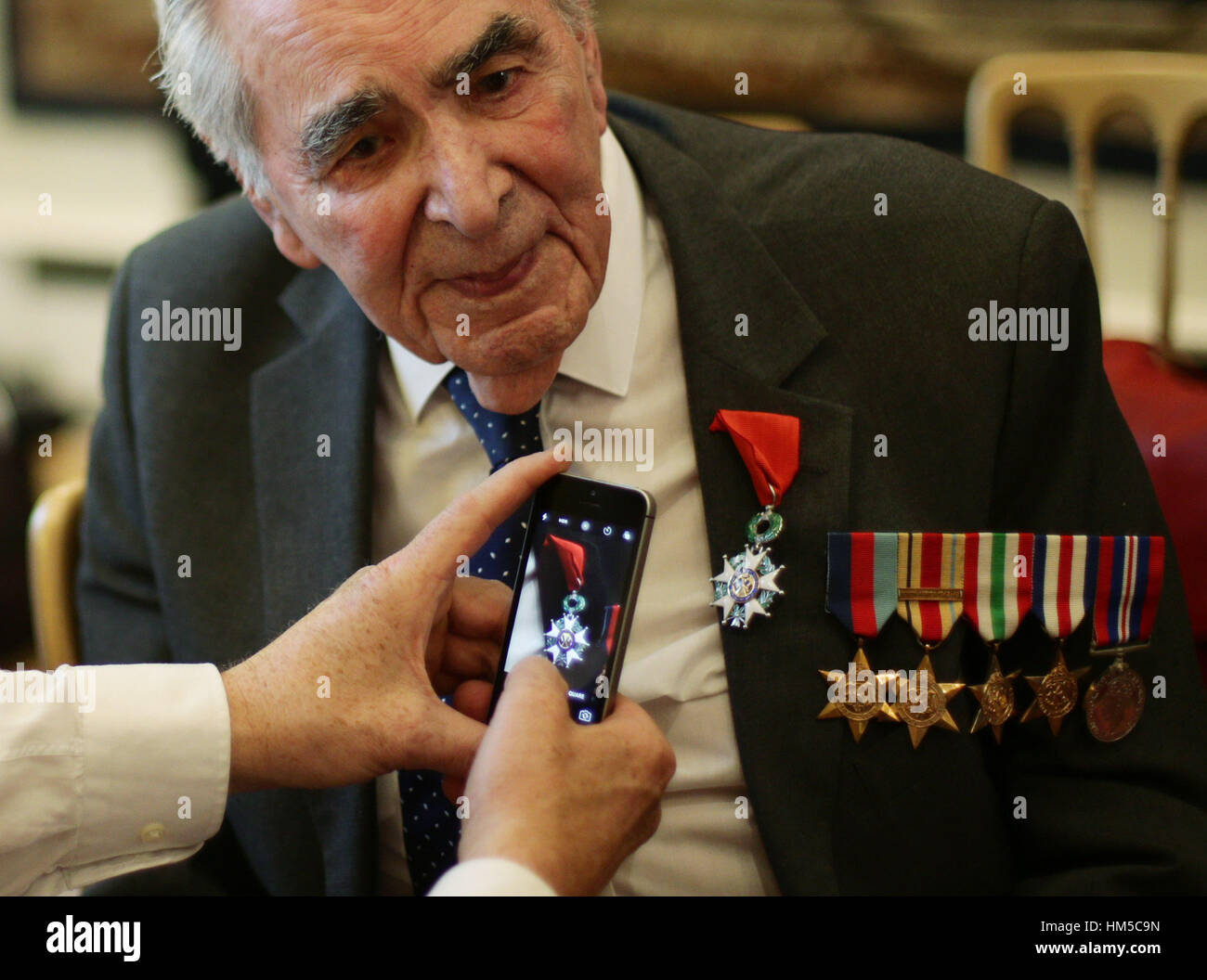 A cameraman takes a photos of Oliver Lucas-Hodge, 93, from Bedfordshire, Signalman in the Royal Navy, during a ceremony for the Legion d'honneur, France's highest distinction, during a ceremony at the French Ambassador's Residence in London. Stock Photo