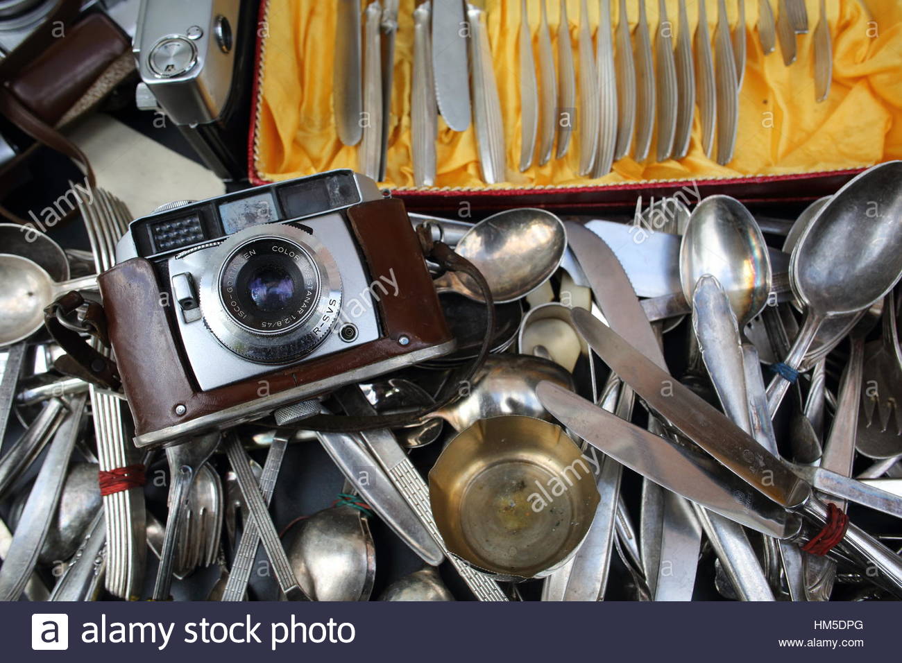 A camera and old silver spoons and knives all flung together in a second hand shop Stock Photo