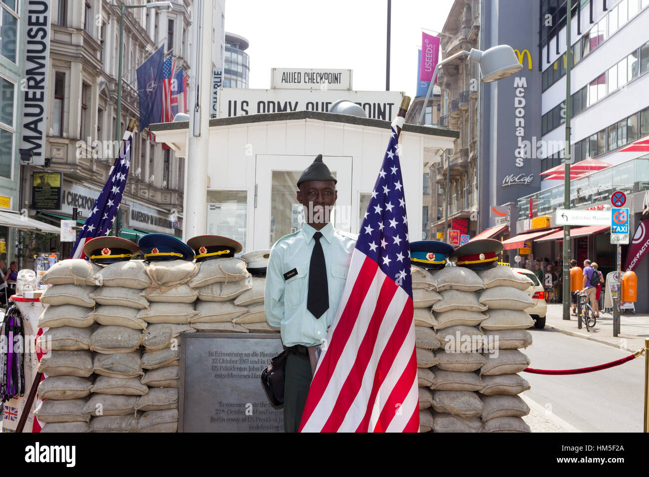 BERLIN, GERMANY - MAY 23: Man dressed as a US Army soldier stands with an American flag at the former Allied checkpoint 'Charlie' on May 23, 2014. Now Stock Photo