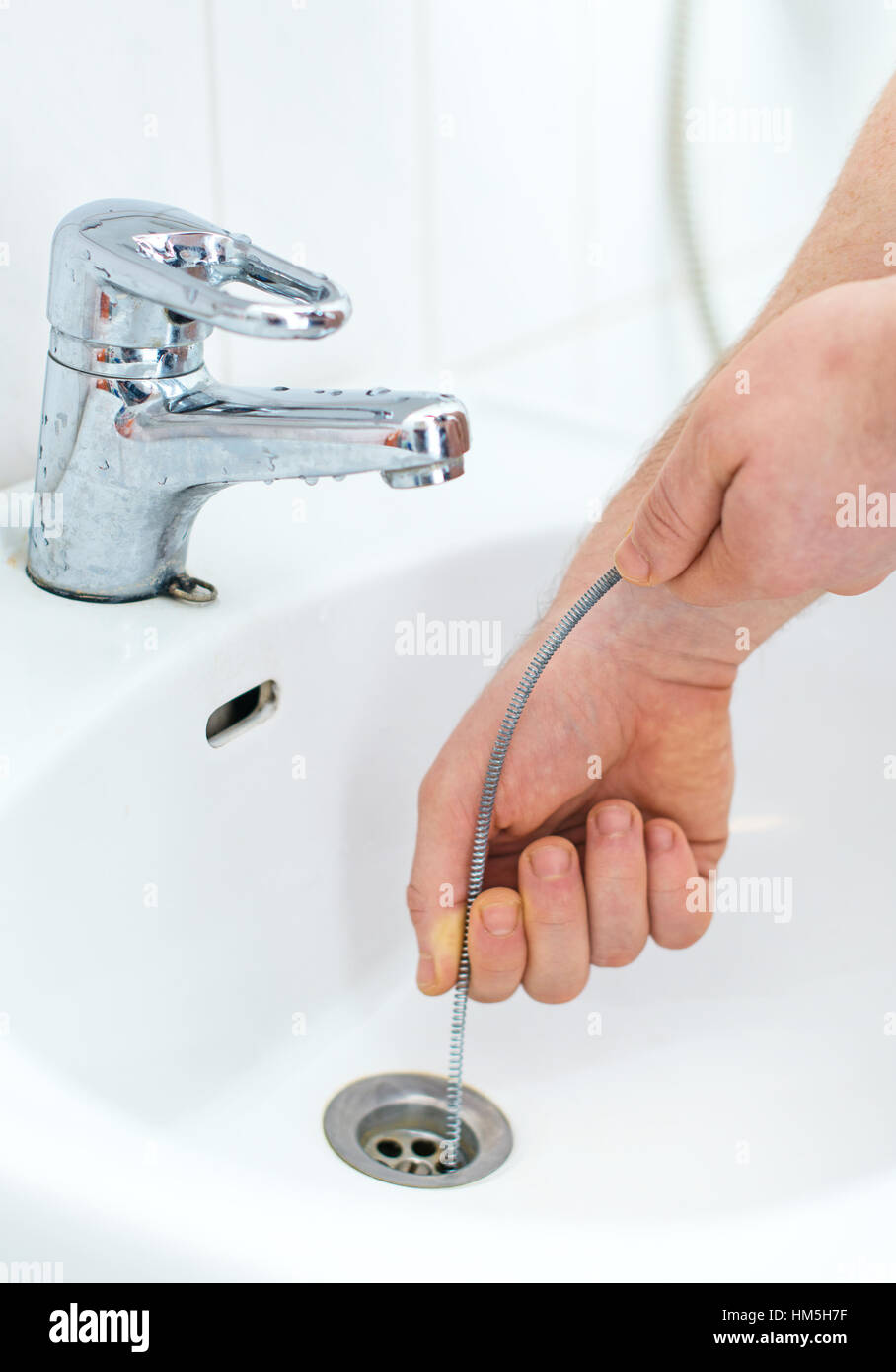Plumber repairing sink with plumber's snake Stock Photo Alamy