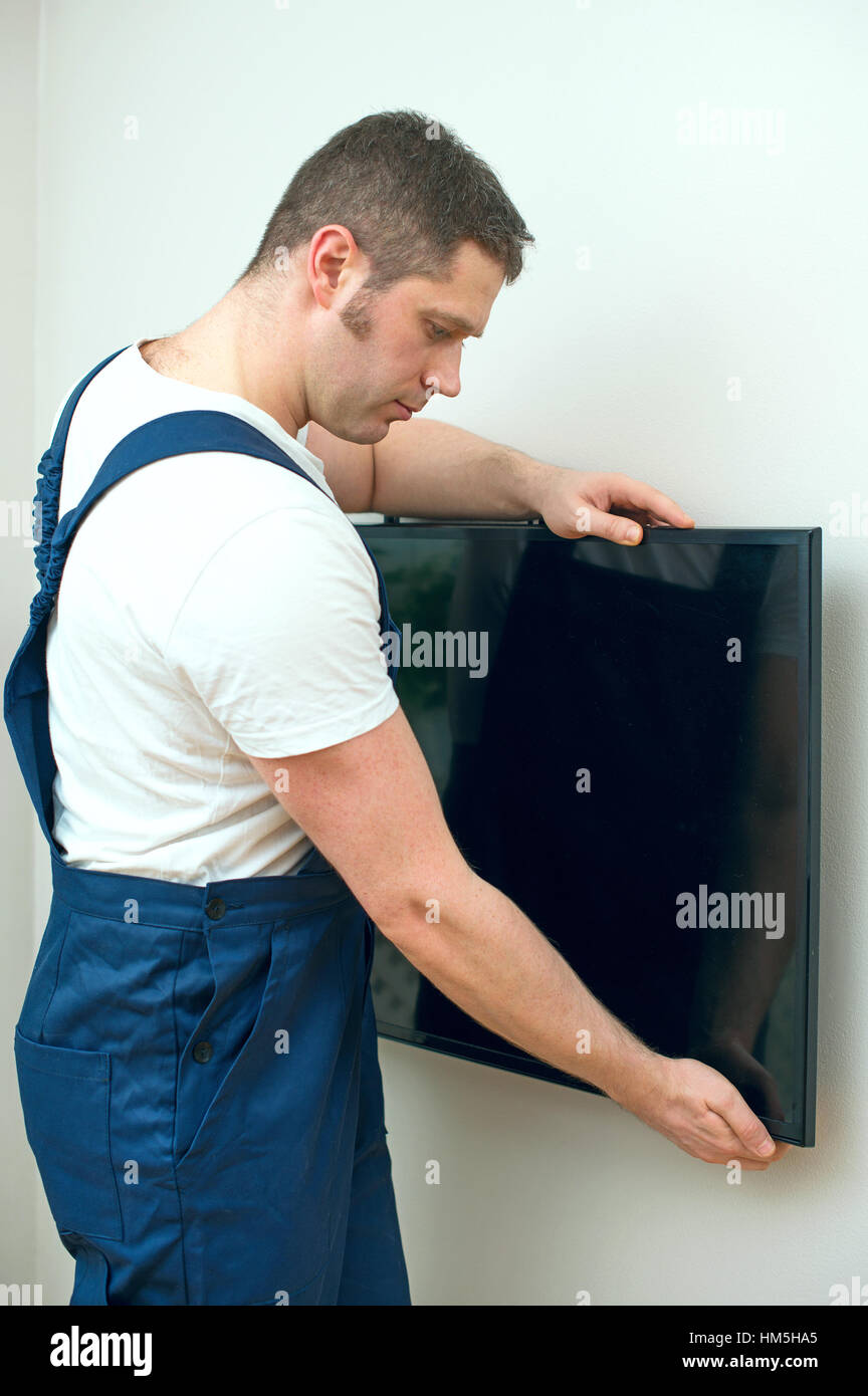 Man mounting TV on the wall. Stock Photo