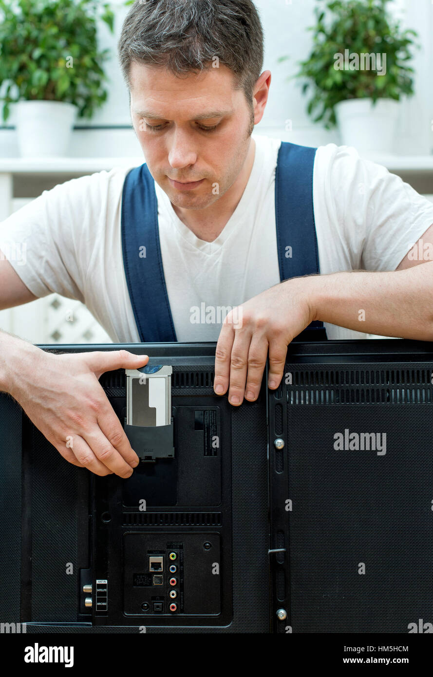 Man installing conditional access module card to TV Stock Photo - Alamy