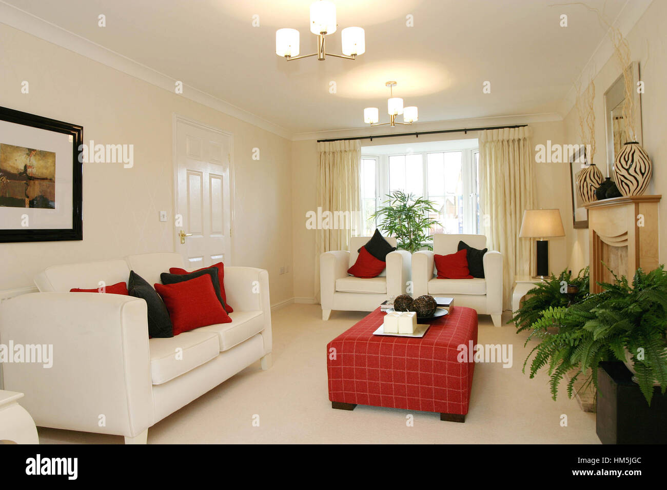 Modern living room interior, cream sofas, red soft furnished coffee table, neautral colouring. Stock Photo