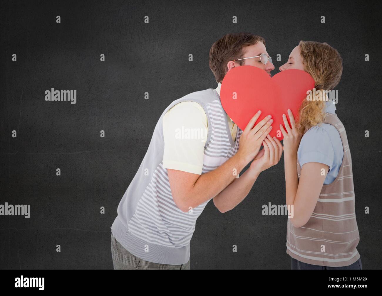 Young couple kissing behind red heart Stock Photo - Alamy