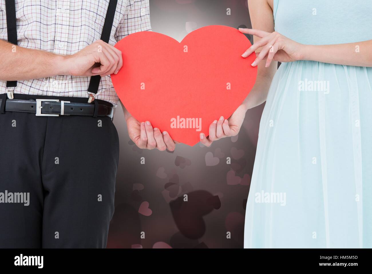 Couple holding a red heart against digitally generated background Stock ...