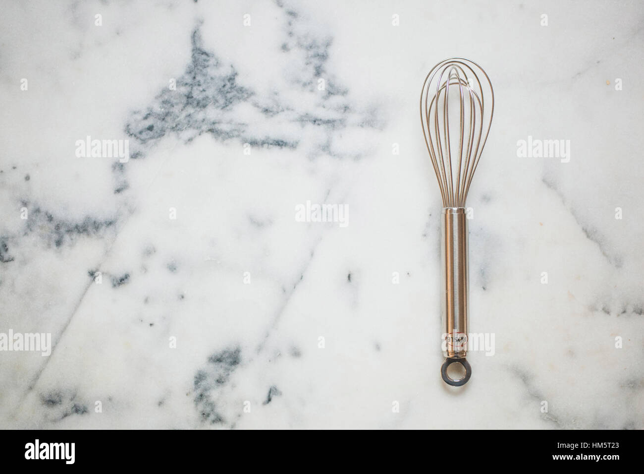 Overhead view of wire whisk on marble Stock Photo
