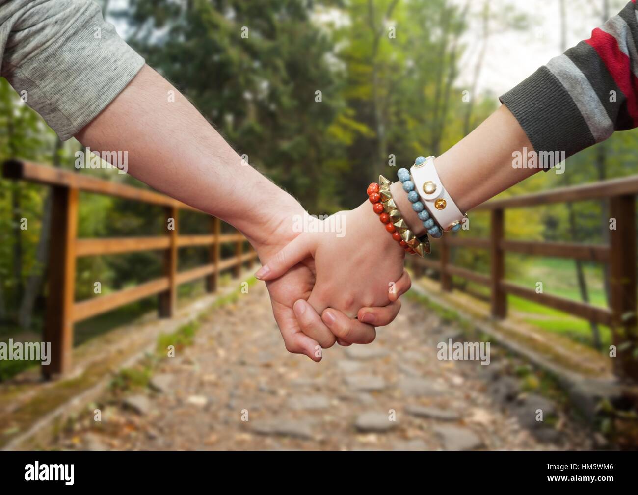 Couple holding hands against park in background Stock Photo - Alamy