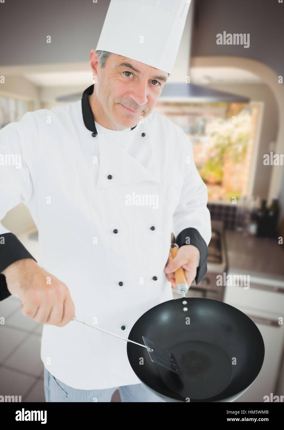Male chef holding frying pan and frying spoon in kitchen Stock Photo