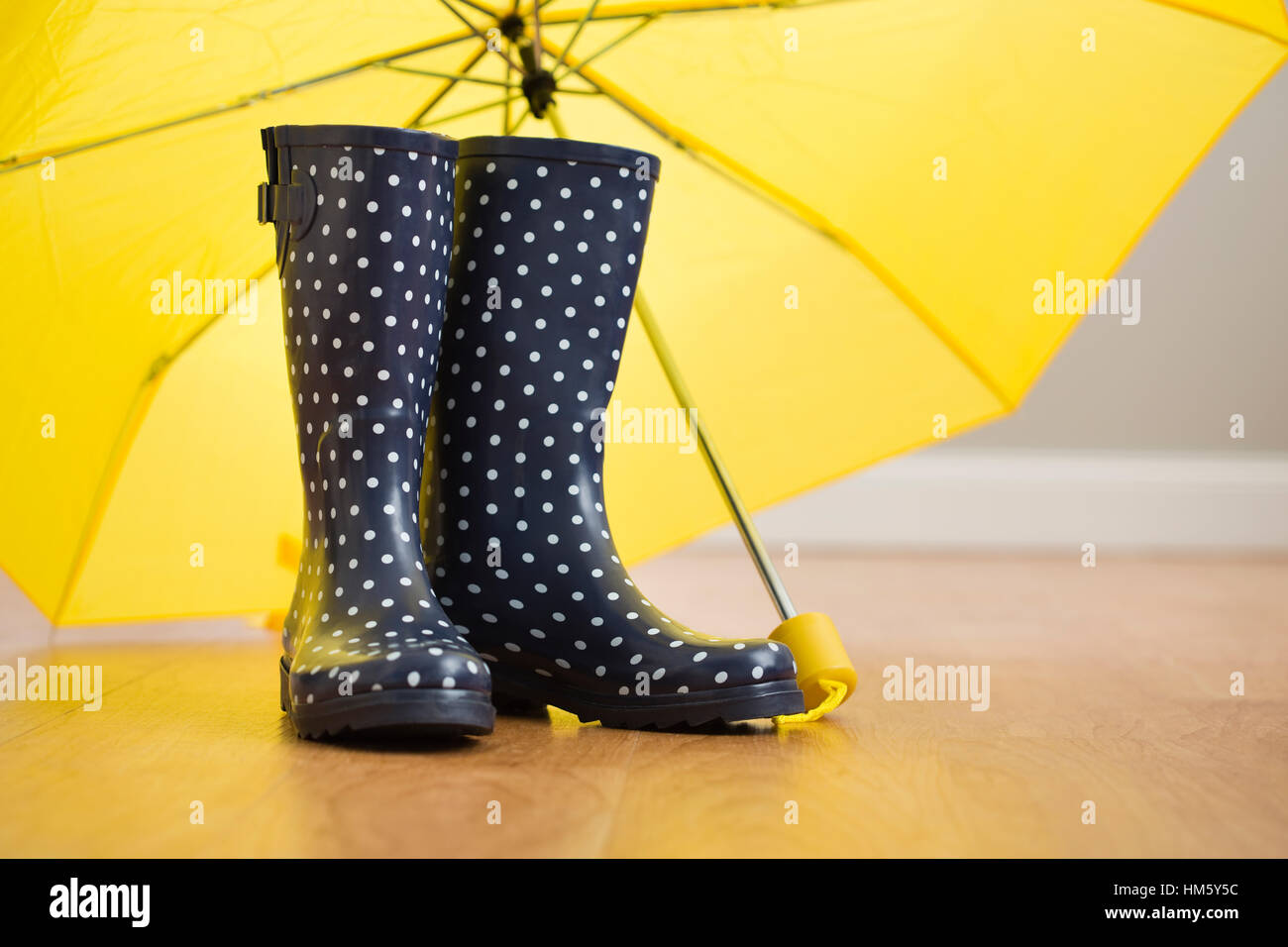 Polka dot wellingtons under yellow umbrella Stock Photo