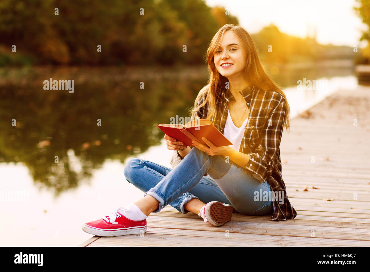 Young beautiful girl sitting on pier Stock Photo