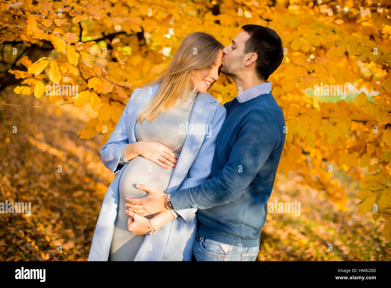 View at pregnant woman and man posing at autumn park Stock Photo - Alamy