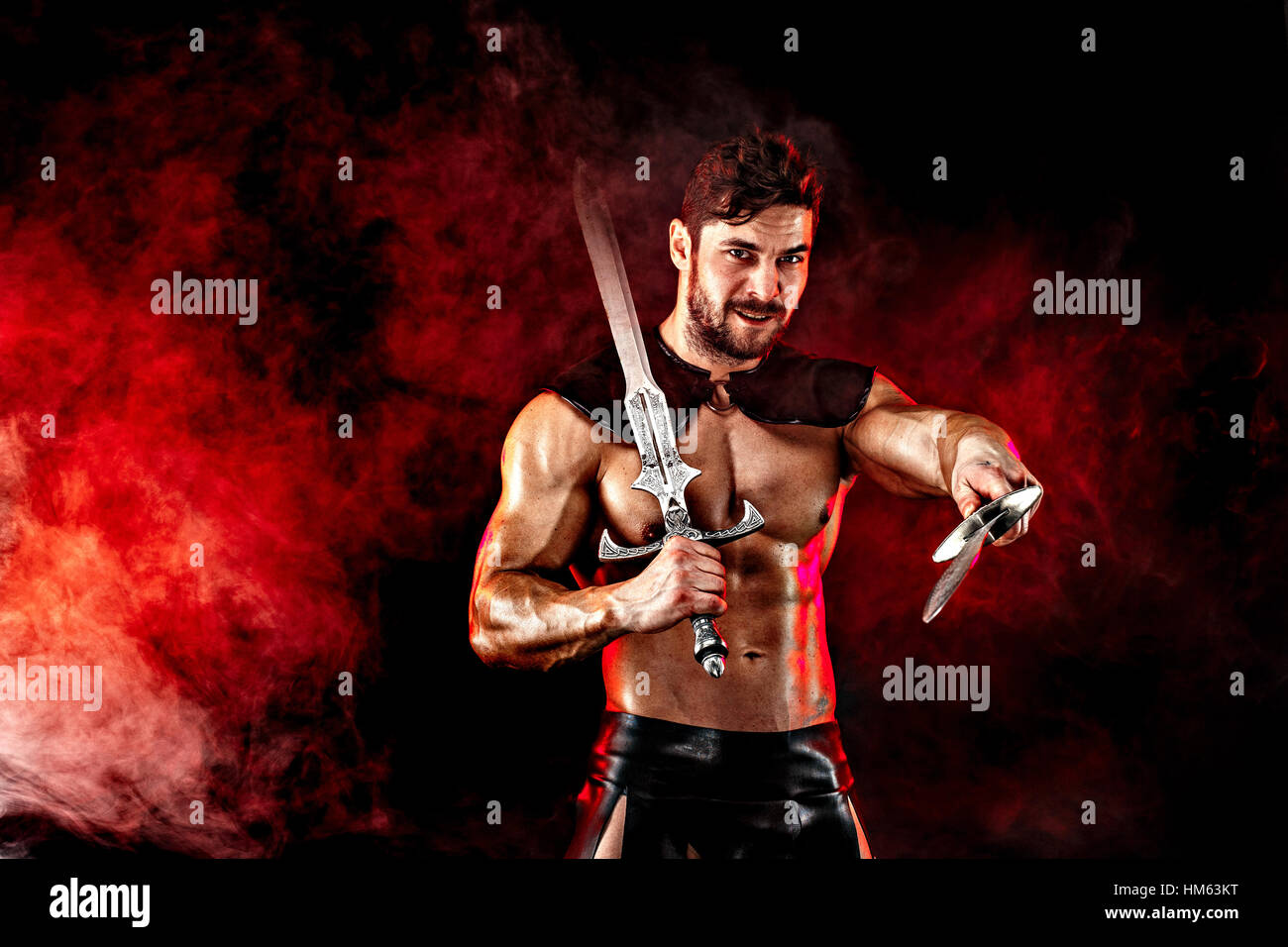 Severe barbarian in leather costume with sword in smoke Stock Photo