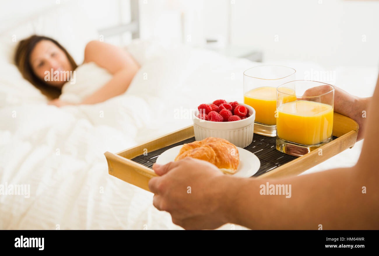 Man carrying breakfast for woman in bed Stock Photo