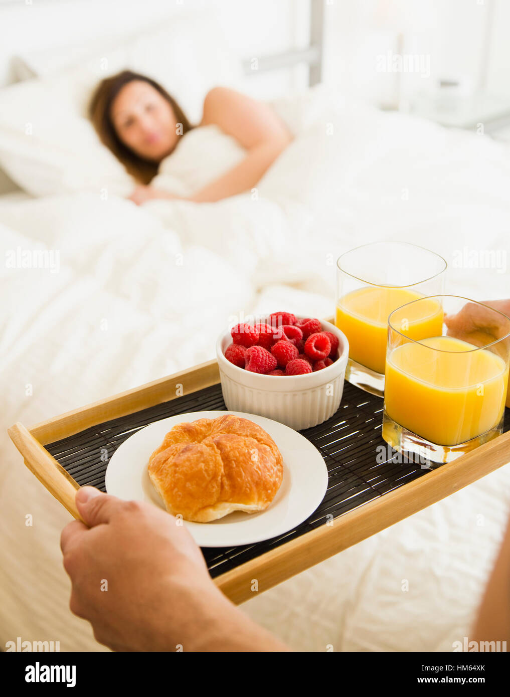 Man carrying breakfast for woman in bed Stock Photo