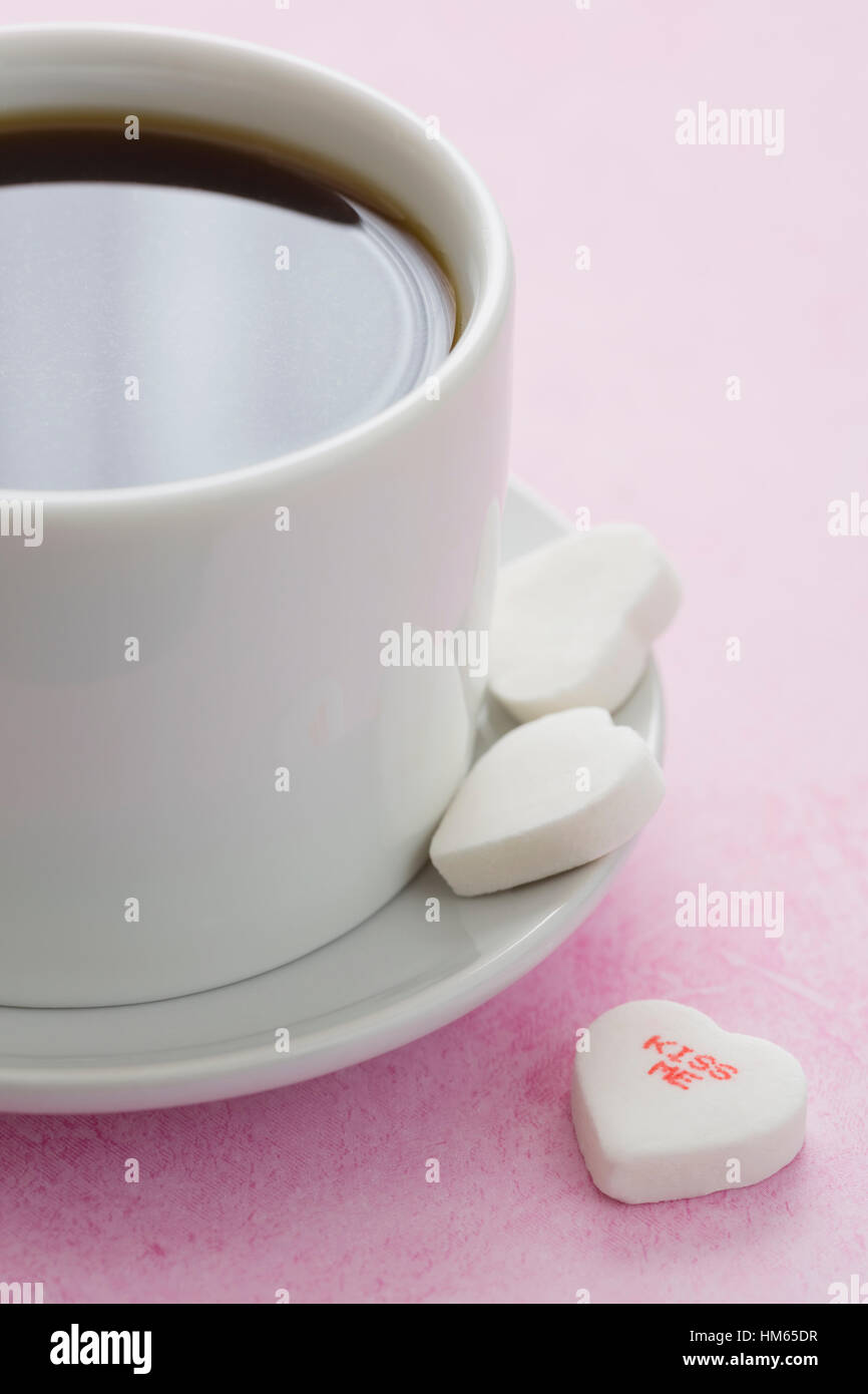 White heart shape candies and cup of coffee on pink surface Stock Photo