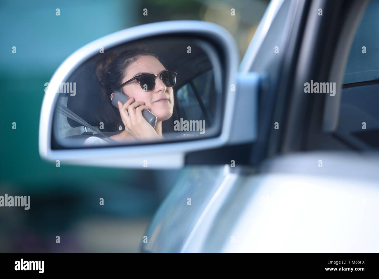 reflection on the mirror of woman talking and driving Stock Photo