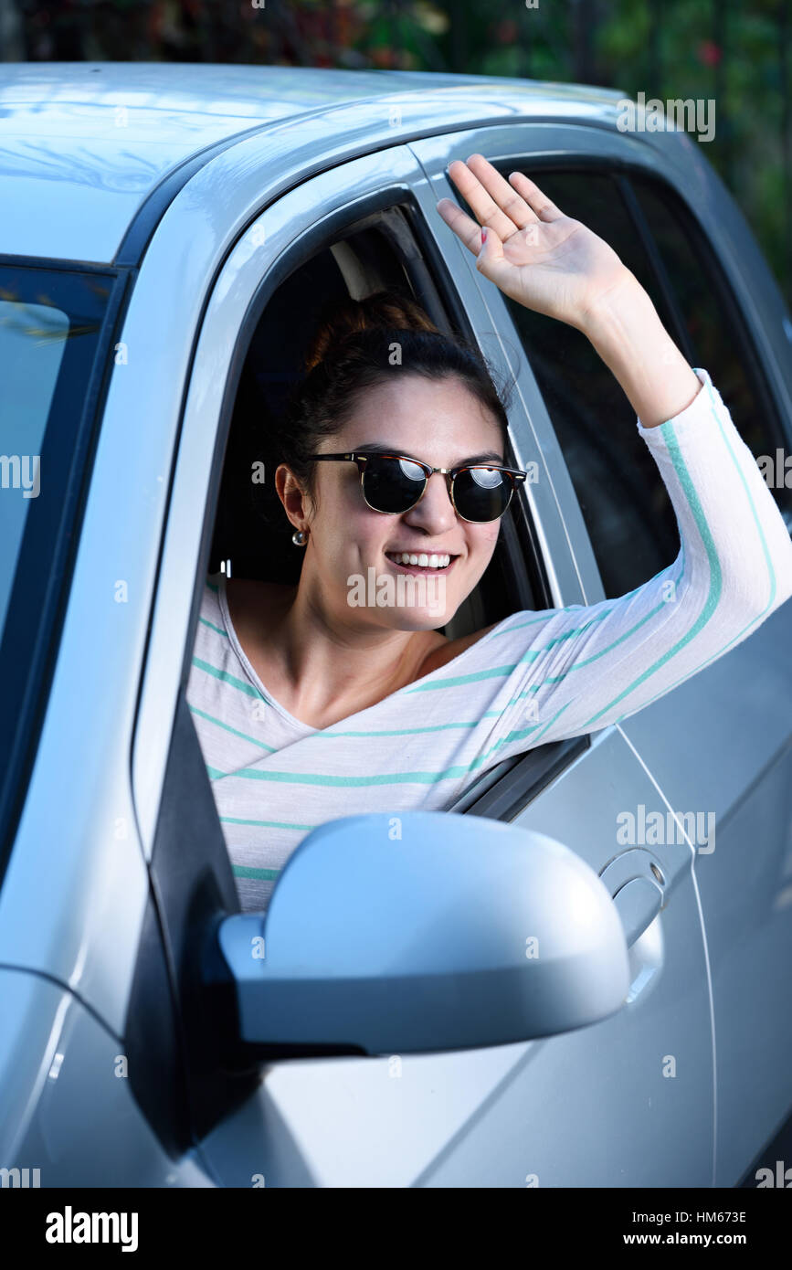 young woman saying hi while driving car Stock Photo Alamy