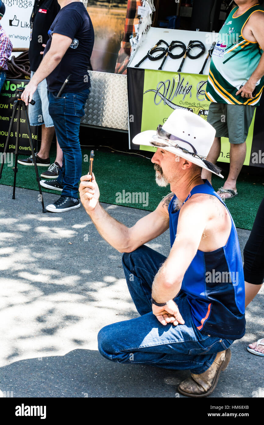 Man in a Cowboy Hat using a smart phone to photograph a Buskers' performance Stock Photo
