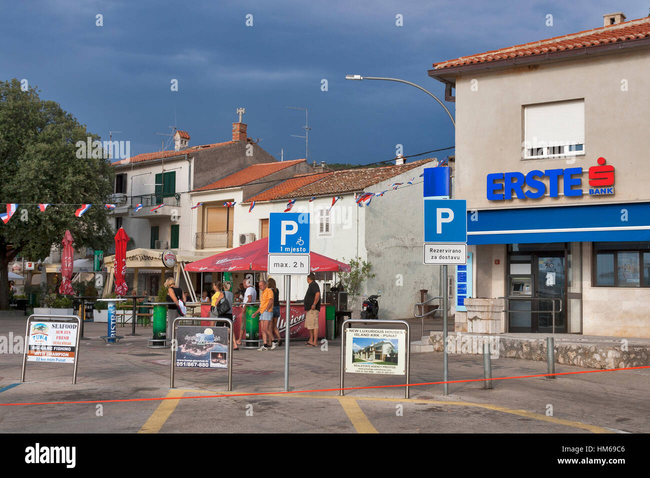 PUNAT, CROATIA - AUGUST 11: Tourists walk along city street in front of Erste Bank on August 11, 2012 in Punat, Croatia. Punat is a municipality in th Stock Photo